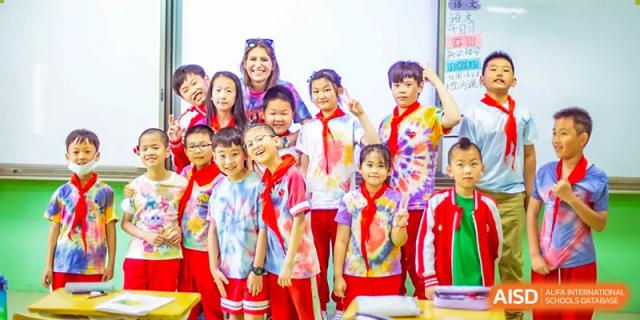 A large group of students from Beijing Concord College of Sino-Canada is posing for a class photo, all wearing matching red and white school uniforms.