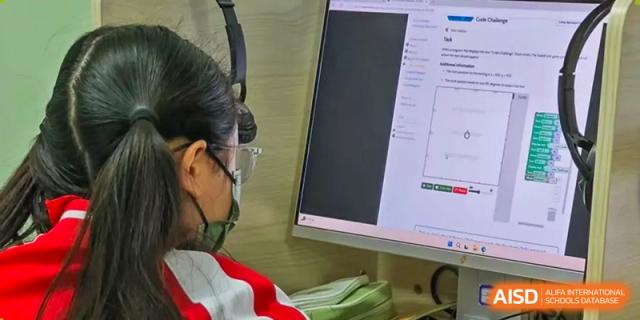 A female student from Beijing Concord College of Sino-Canada is seated at a desk, looking at a computer screen.