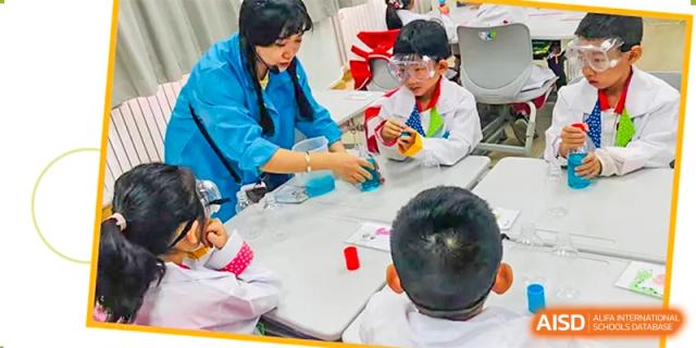 A teacher from Beijing Concord College of Sino-Canada is helping two young students with a hands-on activity at a table.