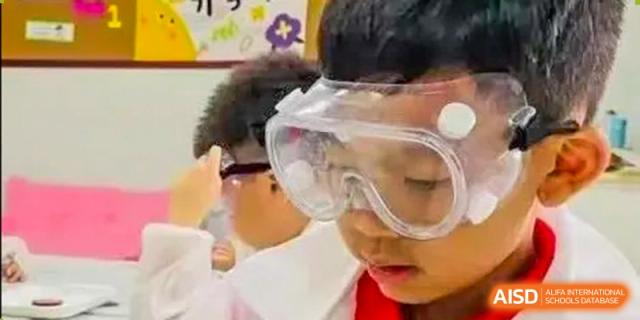 A student from Beijing Concord College of Sino-Canada is wearing goggles and smiling during a science experiment.