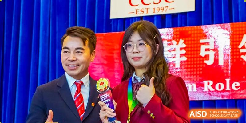 A student from Beijing Concord College of Sino-Canada is receiving an award on stage with a man, with the school logo visible in the background.