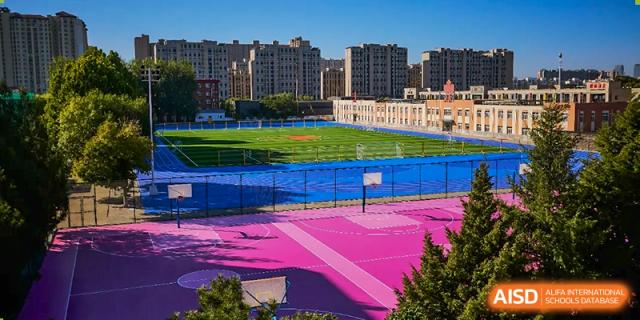An aerial view of a sports track at Beijing Concord College of Sino-Canada, showing a vibrant pink and blue surface.