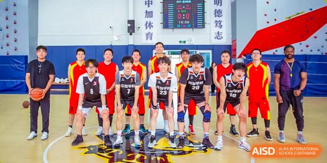 A group of students from Beijing Concord College of Sino-Canada, dressed in basketball uniforms, are posing for a team photo on a court.