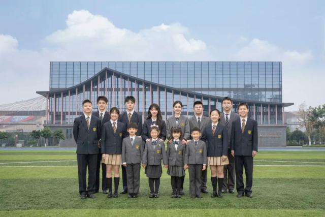 A large group of students from Chongqing BI Academy poses for a class photo on the school's lawn.