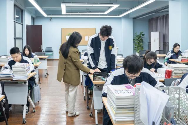 A teacher from Chongqing BI Academy helps a student with a lesson at their desk.