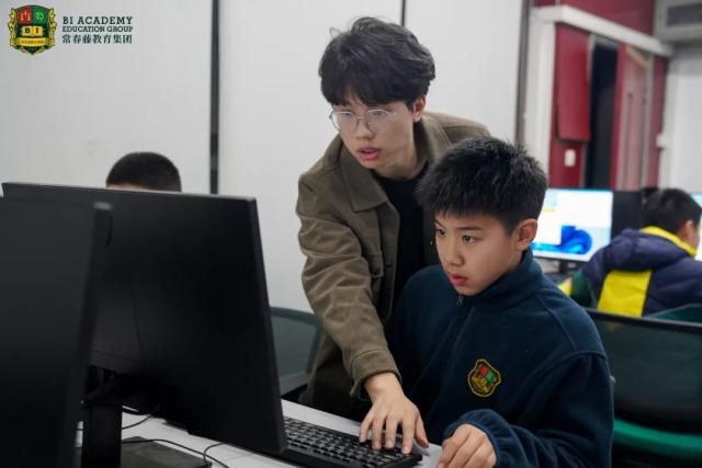 A teacher from Chongqing BI Academy helps a student with a computer in a classroom.