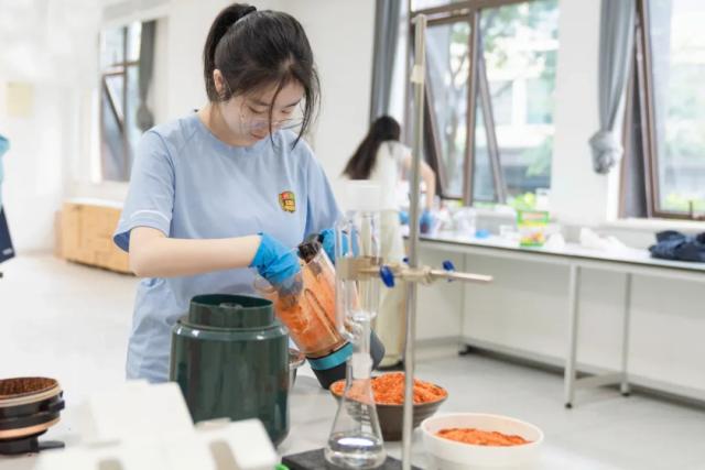 A female student from Chongqing BI Academy pours an orange liquid in a science lab.