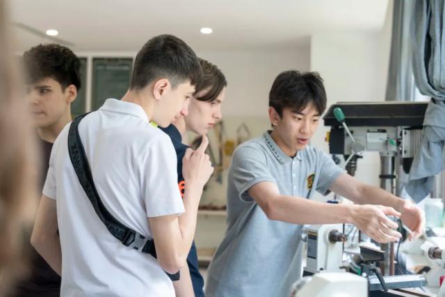 Two male students from Chongqing BI Academy work with a microscope in a science lab.