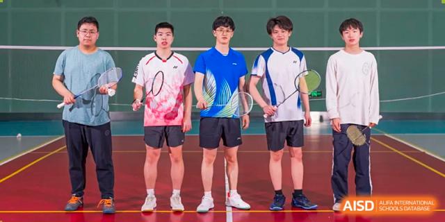 Three male badminton players from Chongqing BI Academy stand with their rackets on a court.