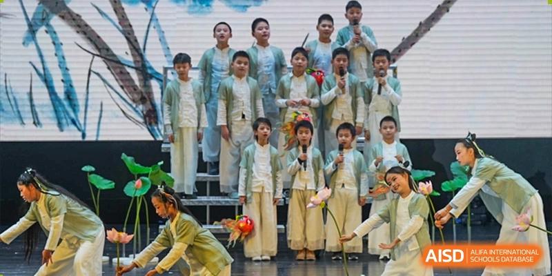 A group of children from Chongqing BI Academy sing on a stage in traditional clothing.
