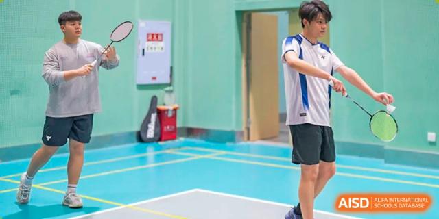 An action shot of two people playing badminton on a court at Chongqing BI Academy.