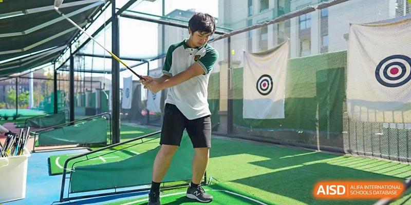 A male student from Chongqing BI Academy practices his golf swing at a driving range.