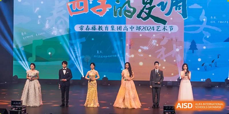 Students from Chongqing BI Academy stand on a stage for a group photo at an event with guests.
