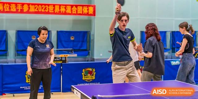 A student from Chongqing BI Academy raises his arm in celebration during a table tennis match.