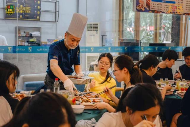 A chef from Chongqing BI Academy helps a student prepare a meal during a cooking class.