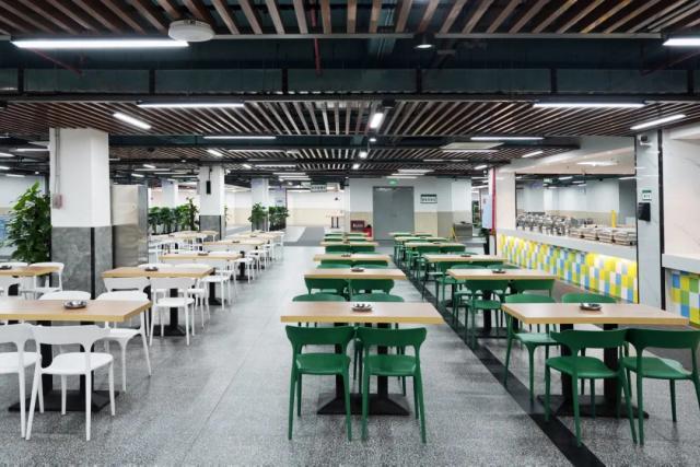 A photo of the empty canteen with green chairs and wooden tables at Chongqing BI Academy.