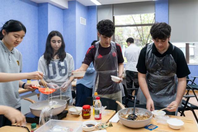 A male student from Chongqing BI Academy works with a female student on a dish during a cooking class.