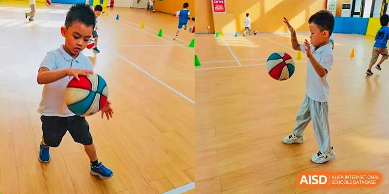 A group of students from EtonHouse International School Nanjing doing a sports drill with cones on a gym floor.