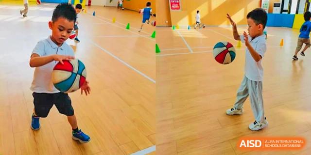 A group of students from EtonHouse International School Nanjing doing a sports drill with cones on a gym floor.