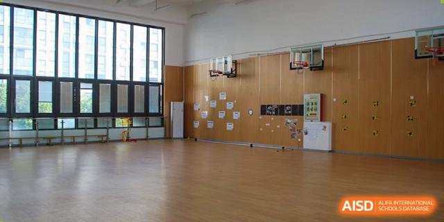 An empty indoor basketball court at EtonHouse International School Nanjing with low hoops for young children.