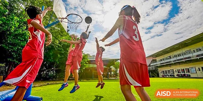 Two students from EtonHouse International School Nanjing playing basketball on an outdoor court.