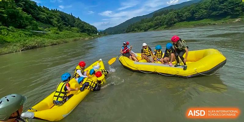 A group of students from EtonHouse International School Nanjing on a yellow raft, paddling on a river.