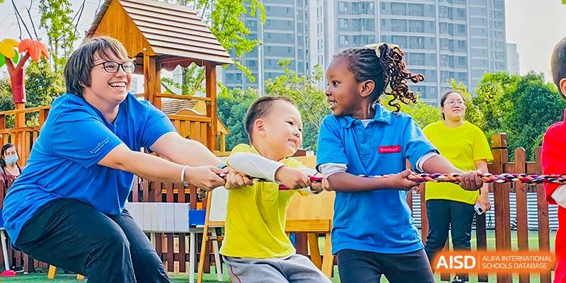 Two young students from EtonHouse International School Nanjing smiling while playing tug-of-war.