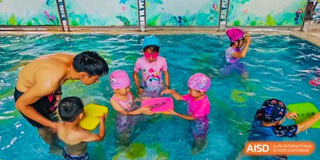 A group of young students from EtonHouse International School Nanjing with an inflatable raft in a swimming pool.