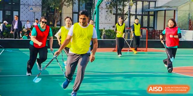 A teacher from EtonHouse International School Nanjing running with a student in a gym.