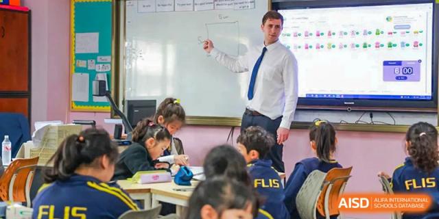 A teacher from EtonHouse International School Nanjing pointing to a whiteboard while teaching a class of young students.