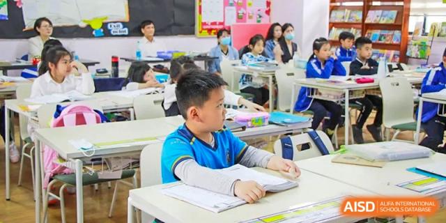 A young student from EtonHouse International School Nanjing writing at a desk in a classroom.