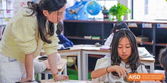 A student from EtonHouse International School Nanjing sitting at a table with a laptop.