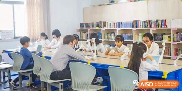 Two students from EtonHouse International School Nanjing sitting at a desk and smiling.