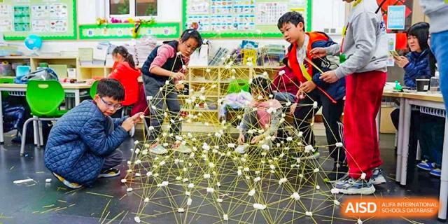 A student from Shanghai Concord Bilingual School shows off a model building project to others.