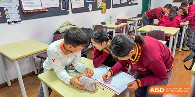 Students from Shanghai Concord Bilingual School work together on their assignments at a table.