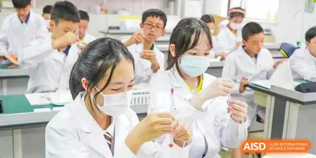 A group of students from Shanghai Concord Bilingual School wear lab coats and masks while conducting a science experiment.