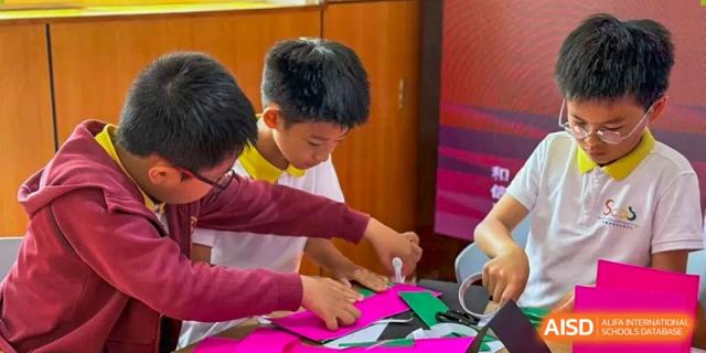 Students from Shanghai Concord Bilingual School are engaged in a crafts activity, using colorful paper.