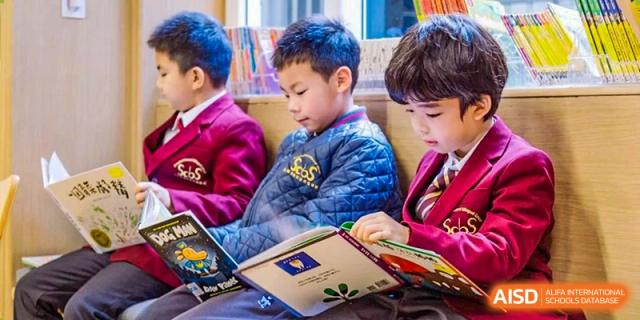 A young male student from Shanghai Concord Bilingual School sits and reads a book.