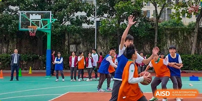 A group of students from Shanghai Concord Bilingual School are playing basketball, with one student reaching to block a shot.
