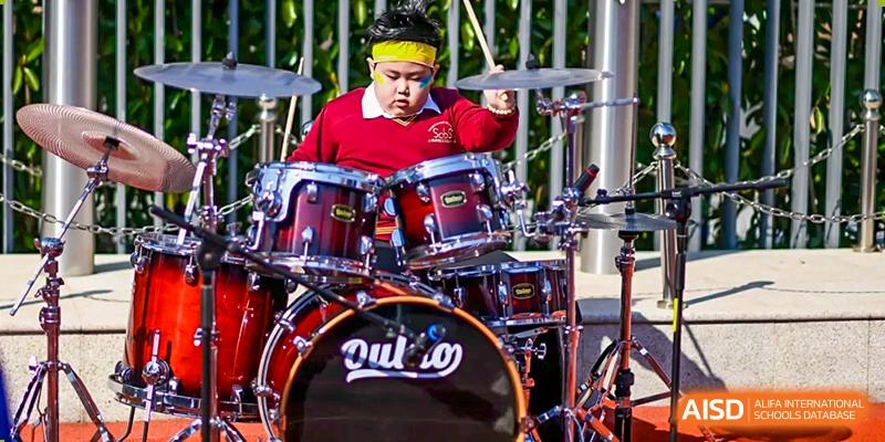 A student from Shanghai Concord Bilingual School plays the drums with focus and intensity.