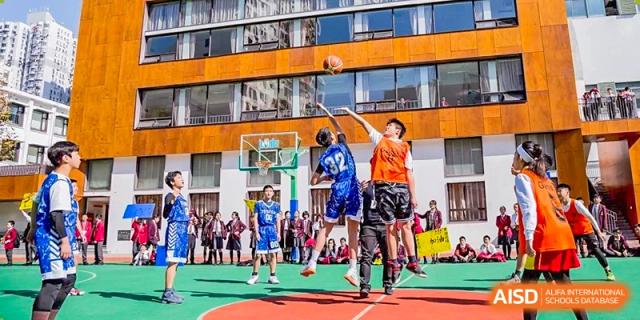 Students from Shanghai Concord Bilingual School are playing a basketball game on an outdoor court.