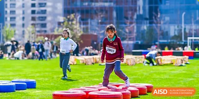A female student from Shanghai Concord Bilingual School walks across a series of red platforms during a race.