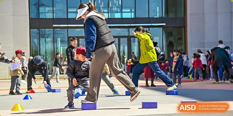 A student from Shanghai Concord Bilingual School participates in an outdoor sport, balancing on a blue block.