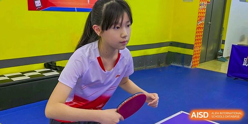 A young female student from Shanghai Concord Bilingual School holds a paddle during a table tennis game.