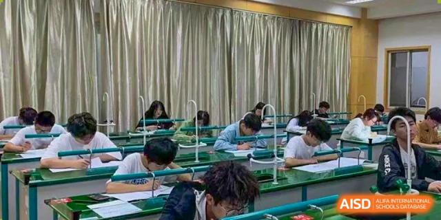 A close-up of students working on written assignments or tests at their desks in a classroom at Wuxi Guanghua School.