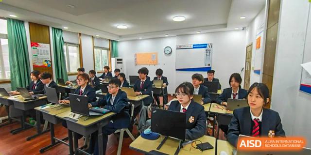 Students working individually on laptops and desks in a computer or technology-enabled classroom at Wuxi Guanghua School.