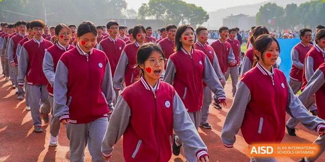 A group of students in red and white jackets marching or walking together at a school event at Wuxi Guanghua School.