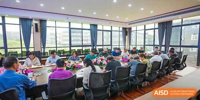 Students and teachers sitting around a large table for a meeting or study group in a conference room at Wuxi Guanghua School.