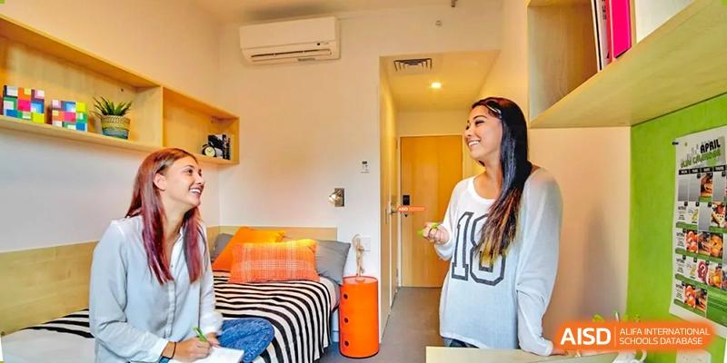 A view of a modern, colorful student dormitory room with a student standing inside at Wuxi Guanghua School.