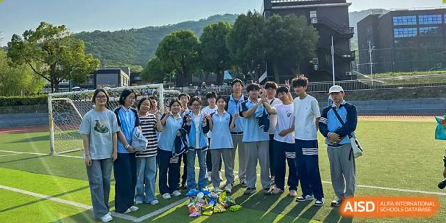 A group of students in uniform gathered outdoors on a sports field, possibly attending a school ceremony or event at Wuxi Guanghua School.